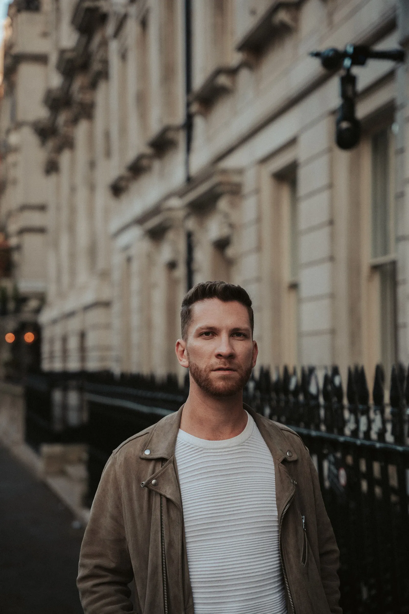 Street portrait of a man in a suede jacket on a Georgian terrace at dusk
