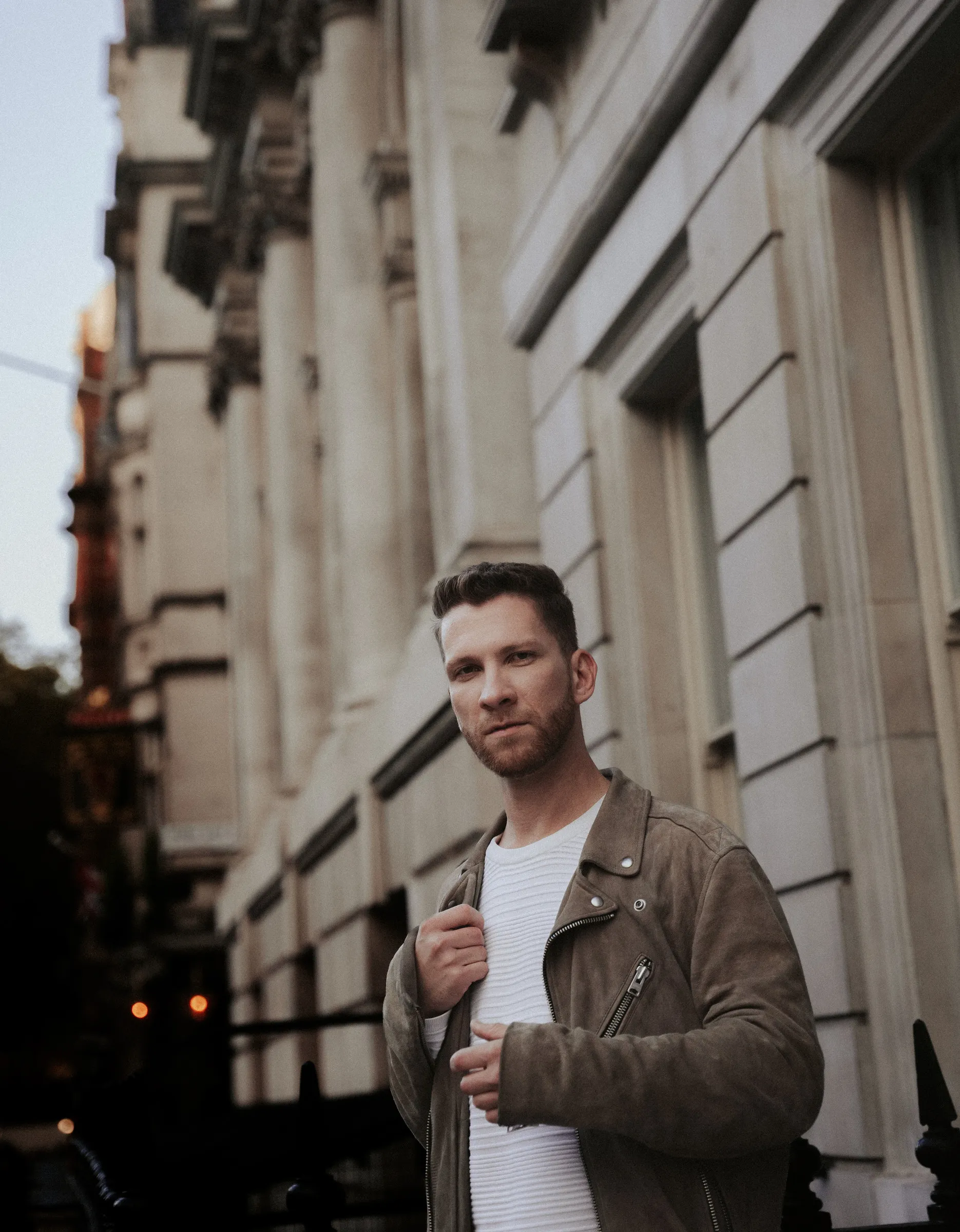 A man leaning against railings on a London street in evening light