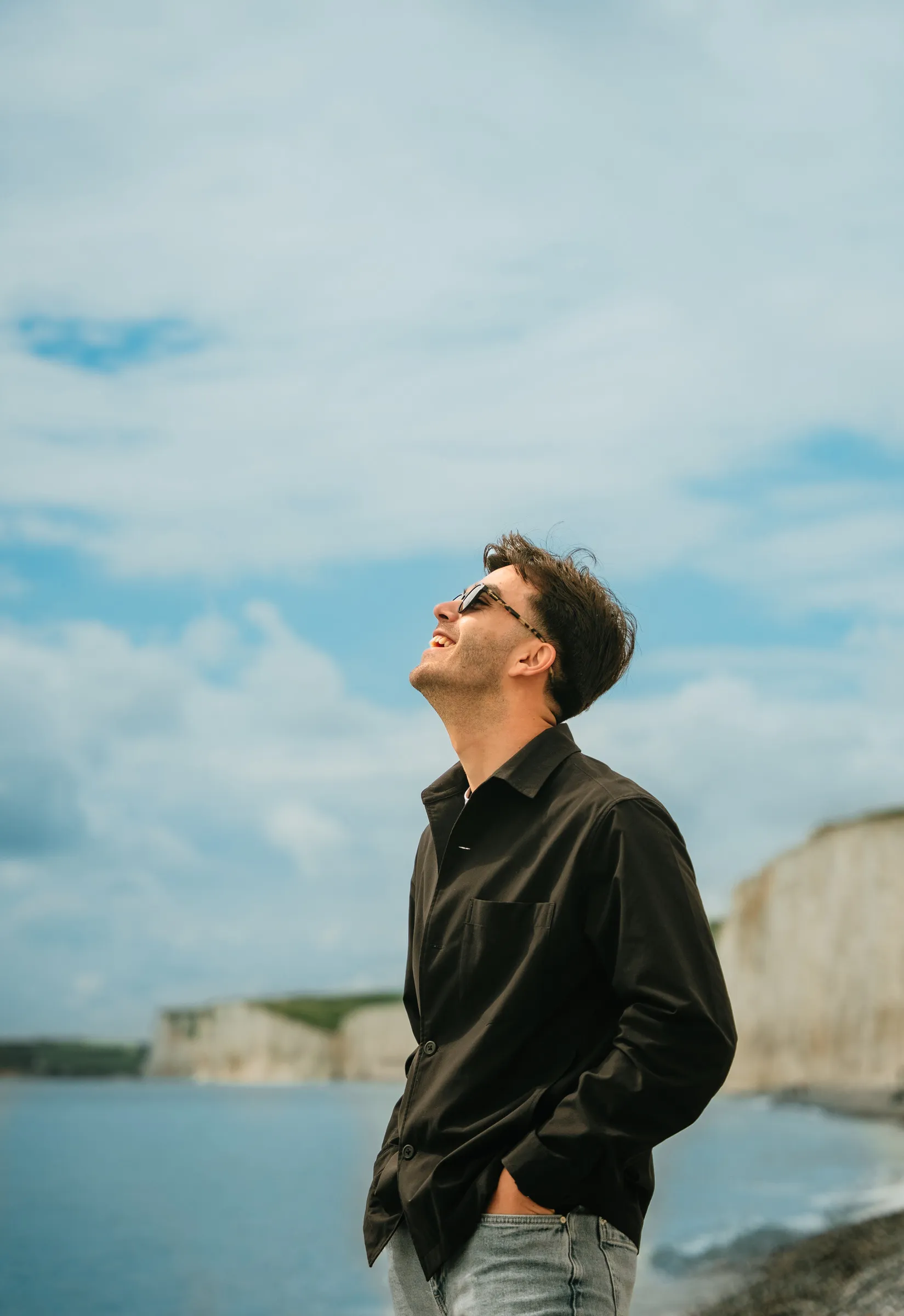 A man standing on the coast path with white chalk cliffs behind him