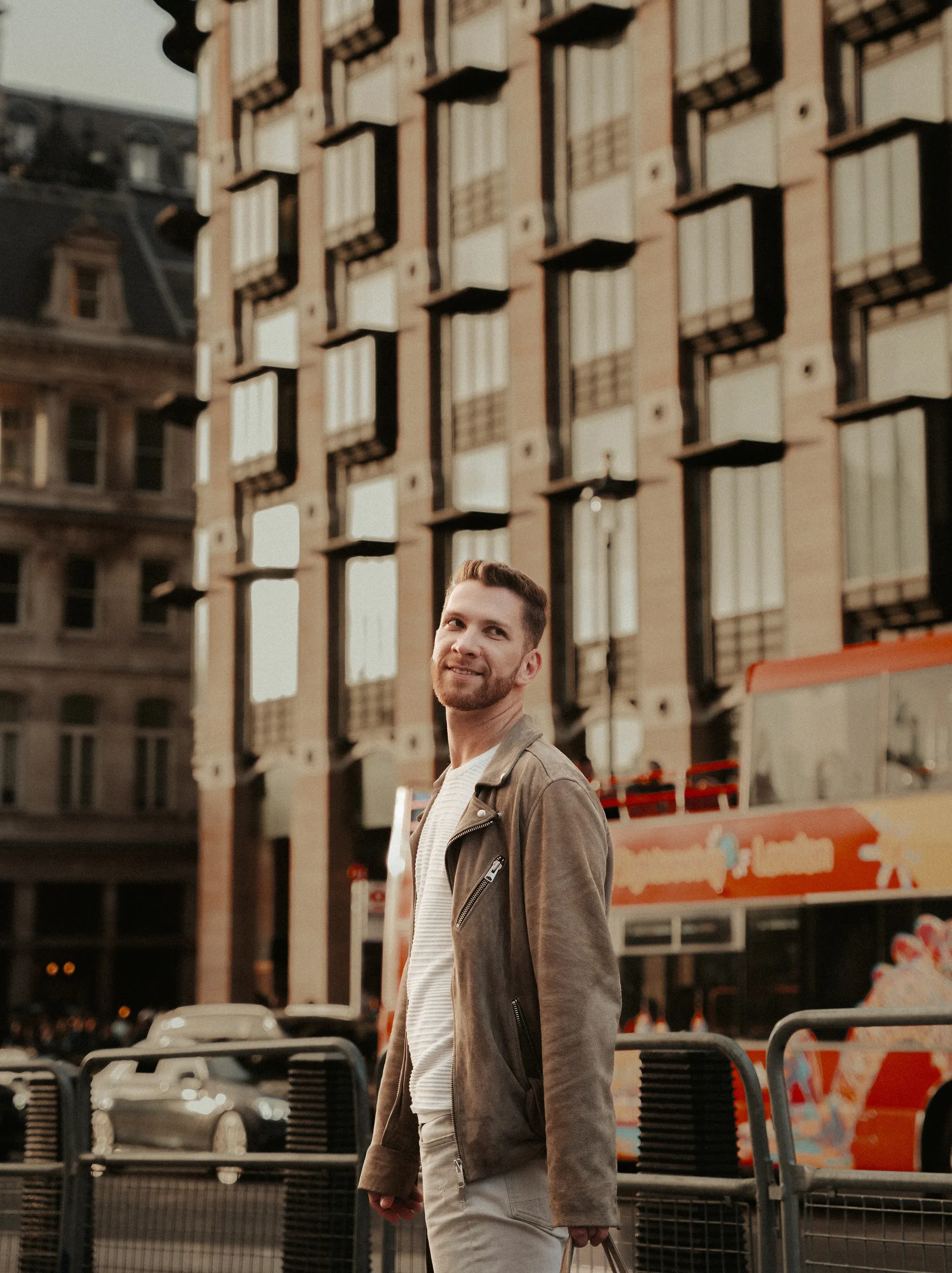 A man in a linen jacket standing in front of a Portland stone facade