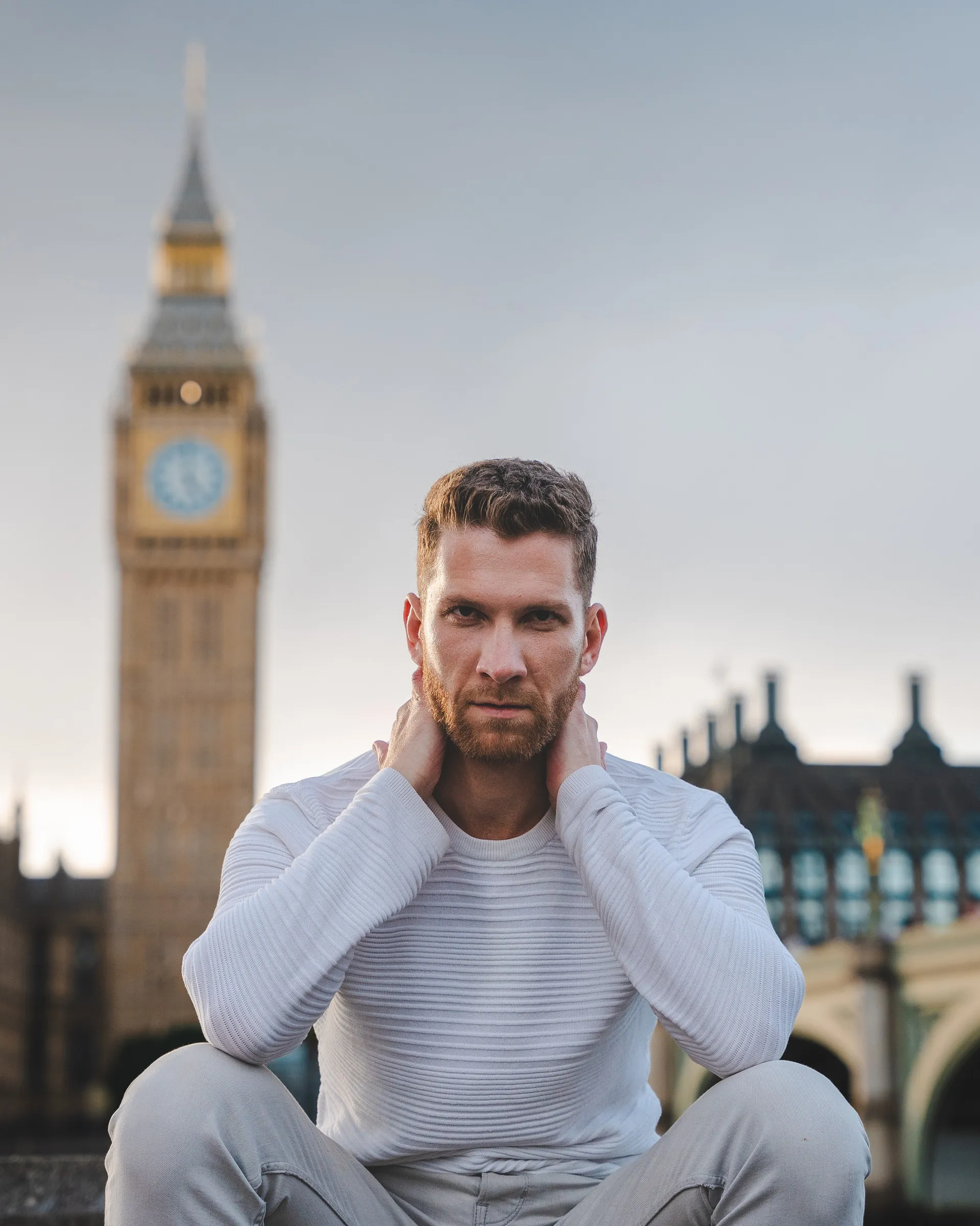 A man seated on a wall with the Elizabeth Tower rising behind him