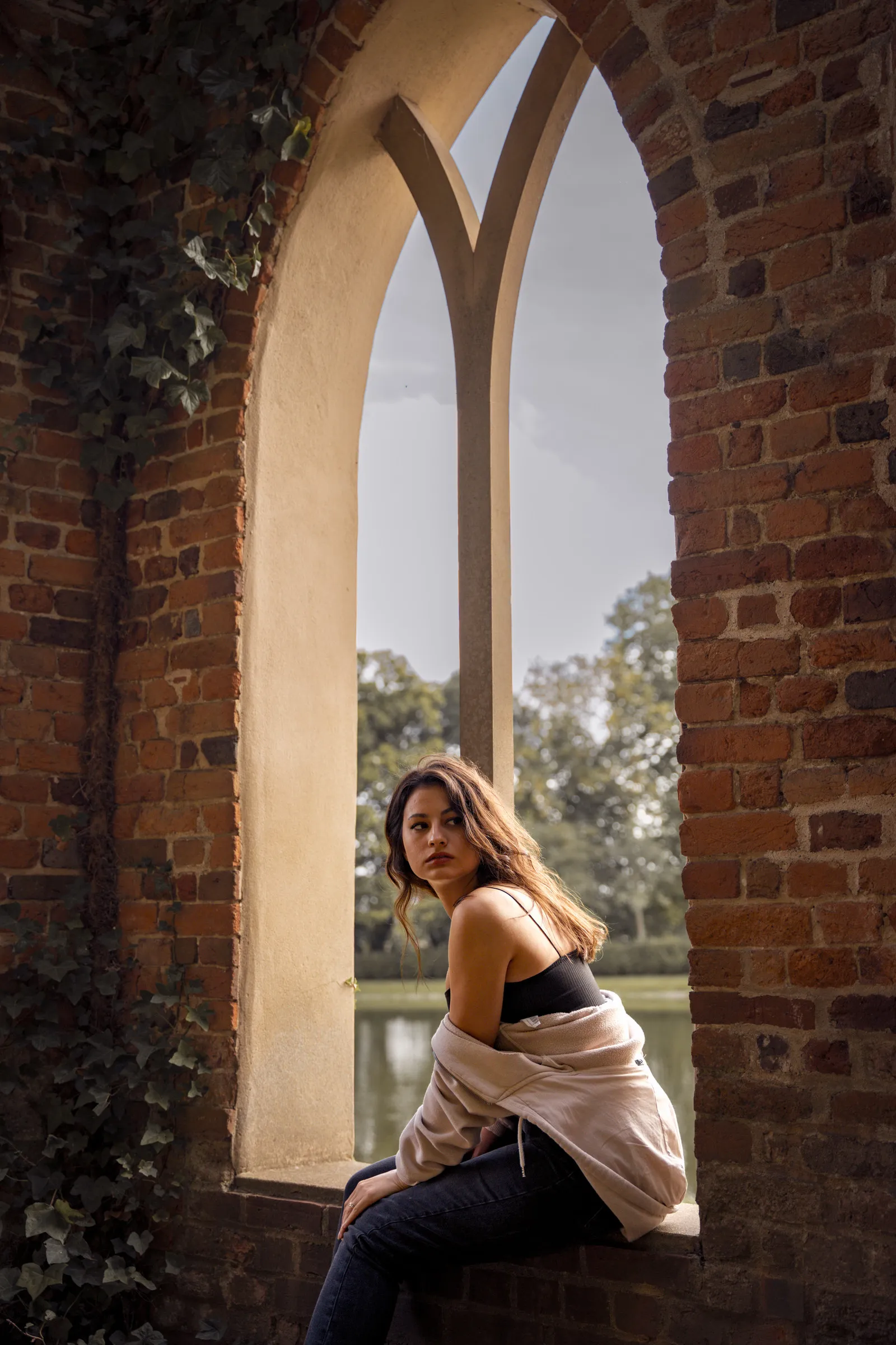 A woman framed by a gothic stone archway in a ruined chapel