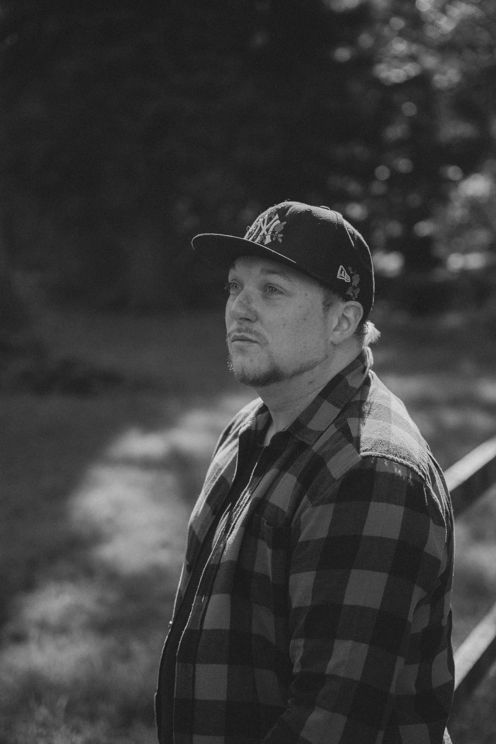 Black and white portrait of a man in a cap and checked shirt outdoors