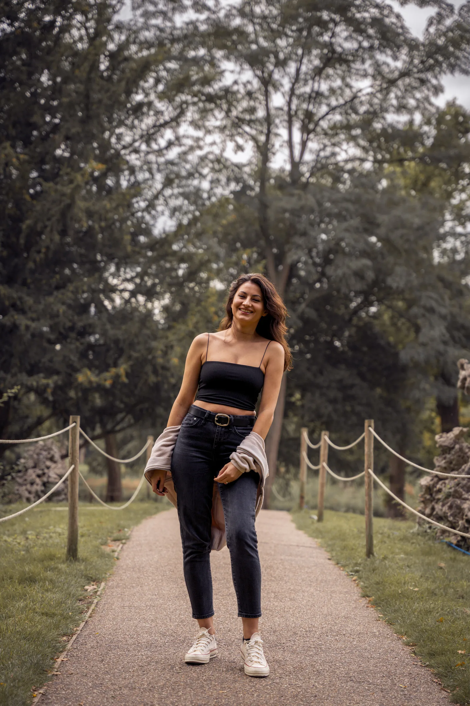 A woman walking towards camera along a tree-lined park path