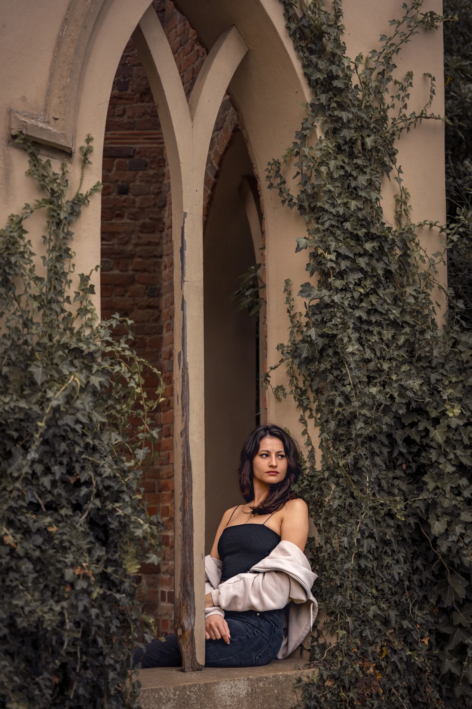 A woman seated in an ivy-covered gothic archway