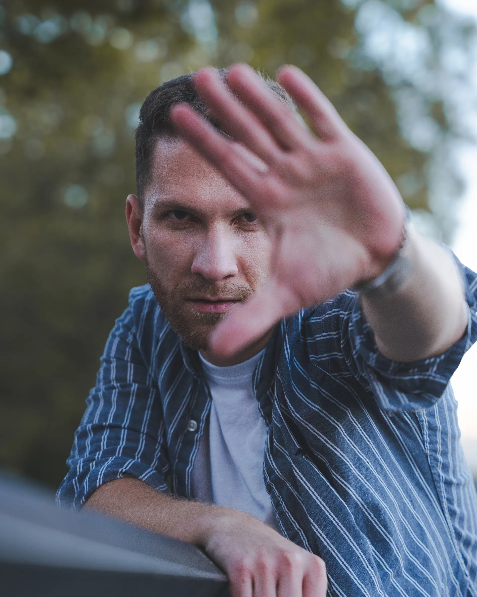 A man reaching a hand towards the camera lens, shallow depth of field