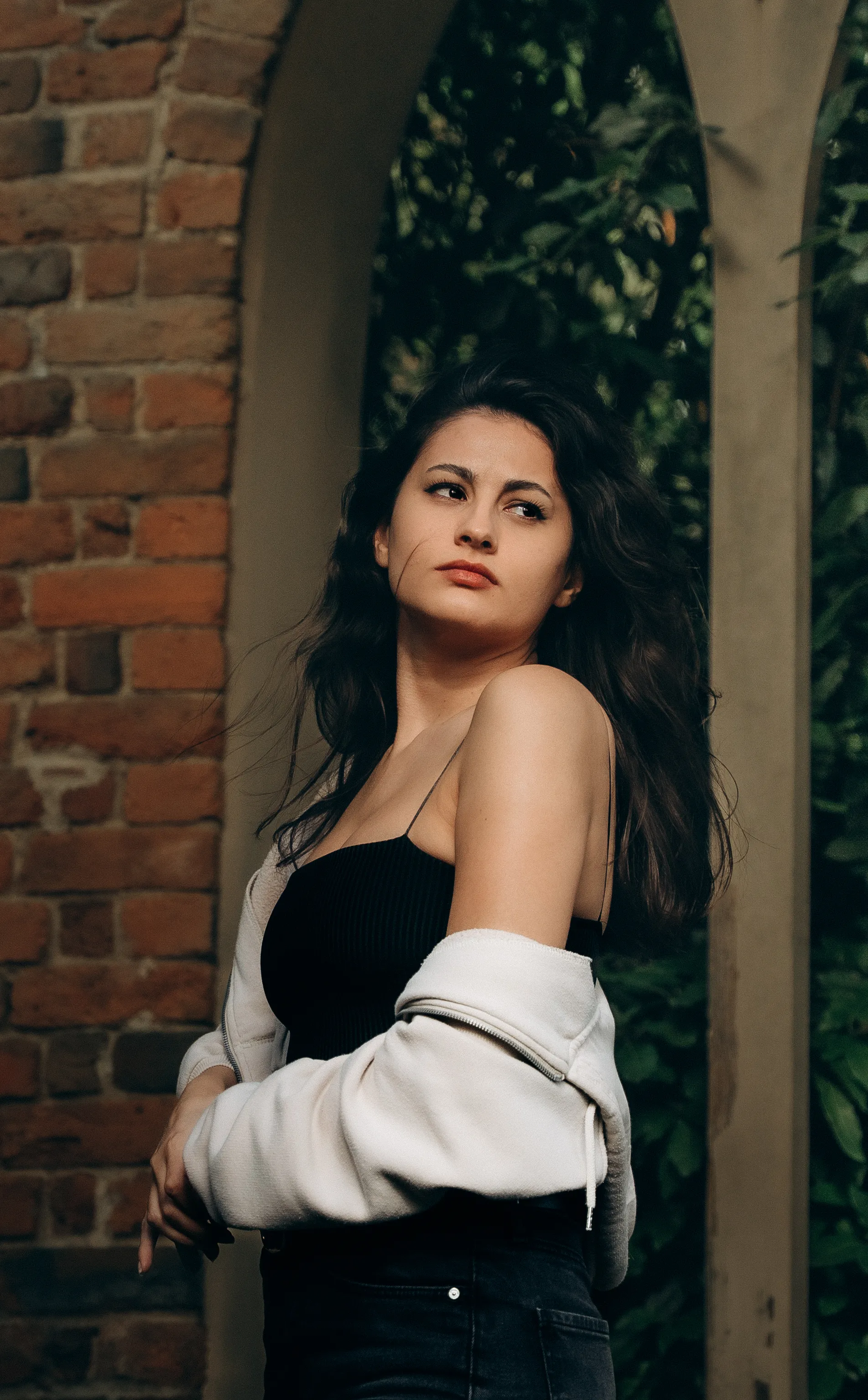 a woman standing by a brick building, captured in natural light with a relaxed and editorial feel