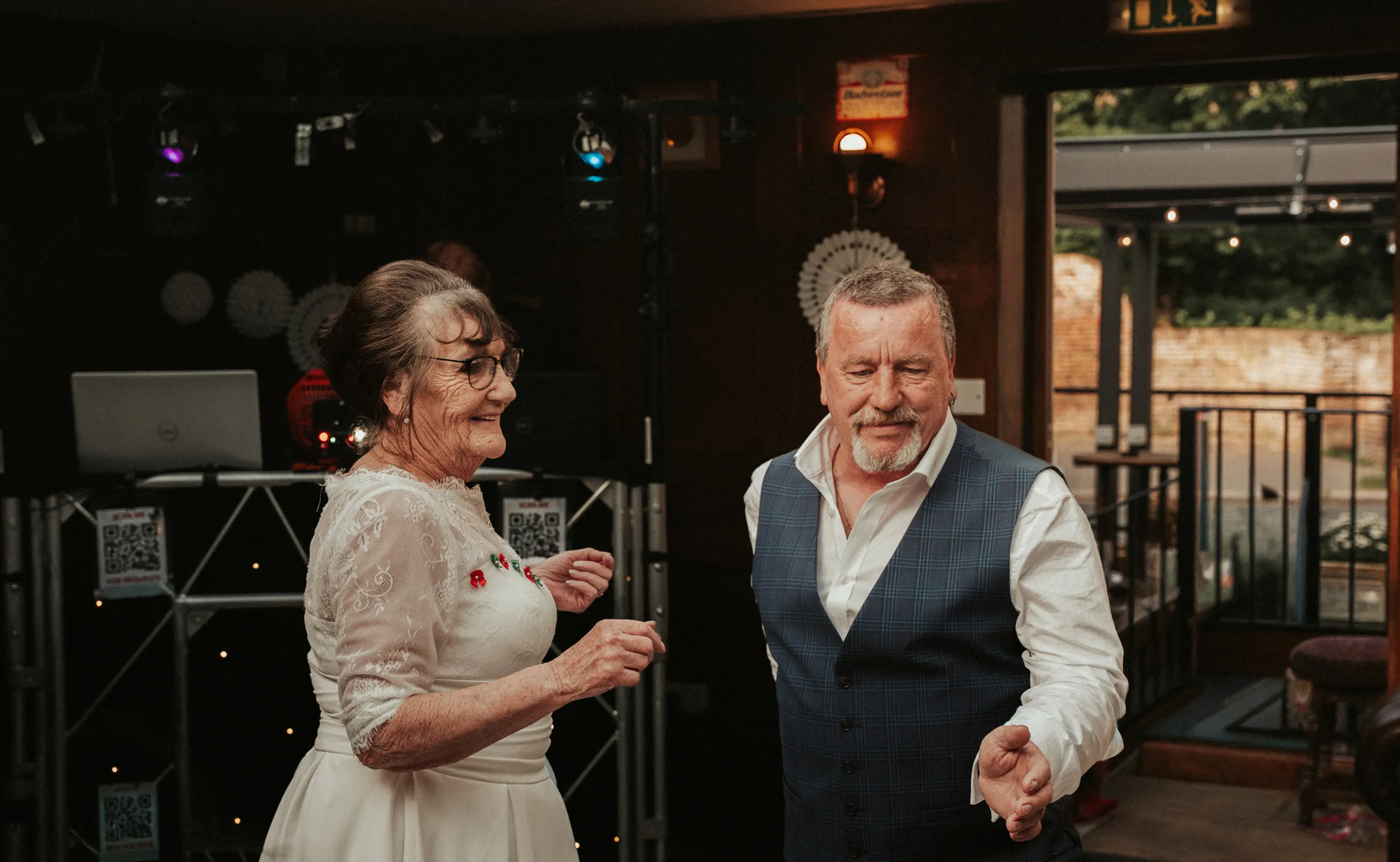 The newlyweds laughing together on the dance floor at their evening reception