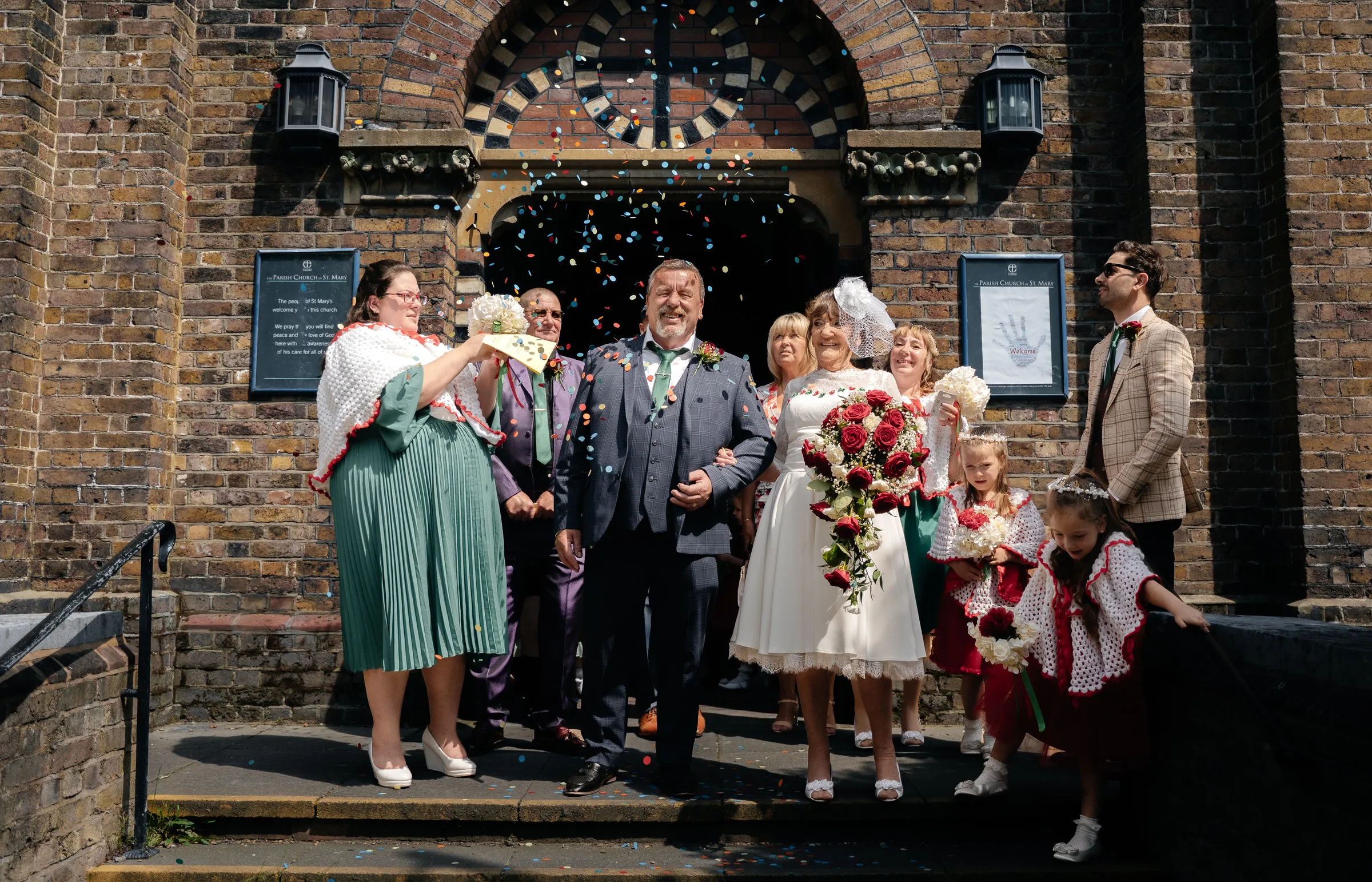 Wedding guests gathered on the church steps beneath a floral arch