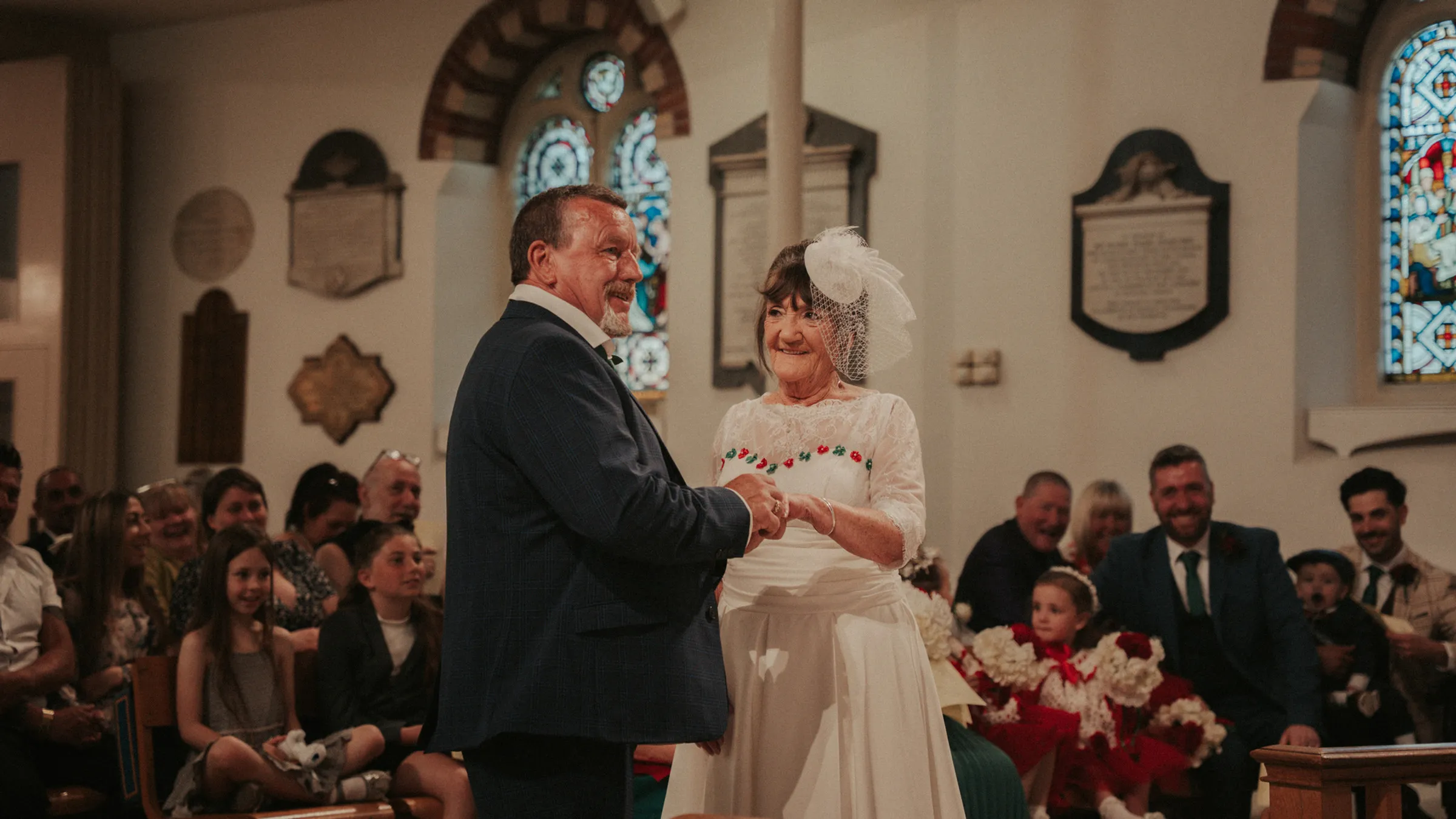 The groom placing the ring on the brides finger as guests look on